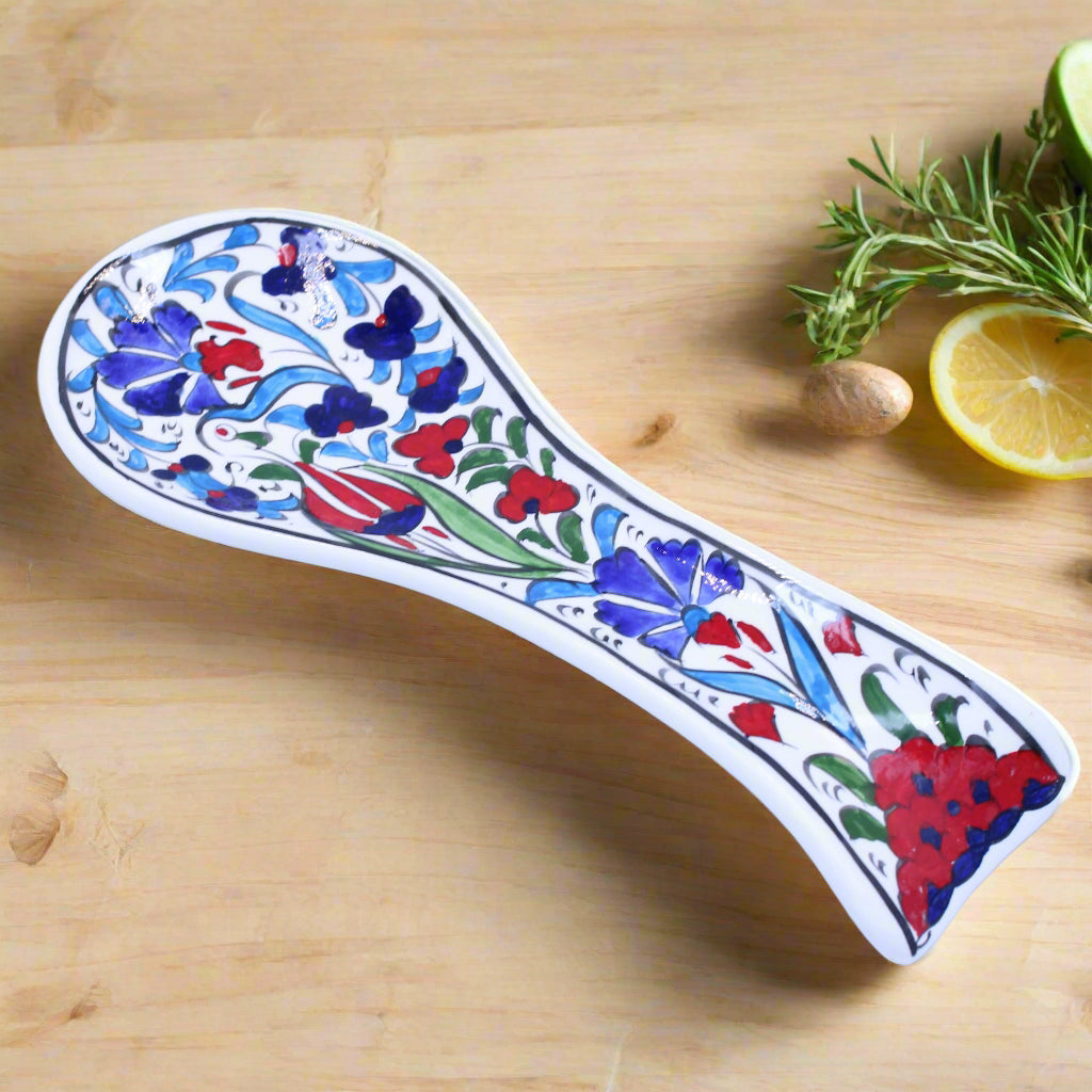 Decorative ceramic spoon rest with floral patterns on a light blue background
