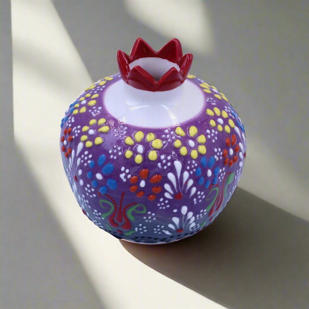 Decorative purple container with colorful floral patterns and a red lid on a light blue background