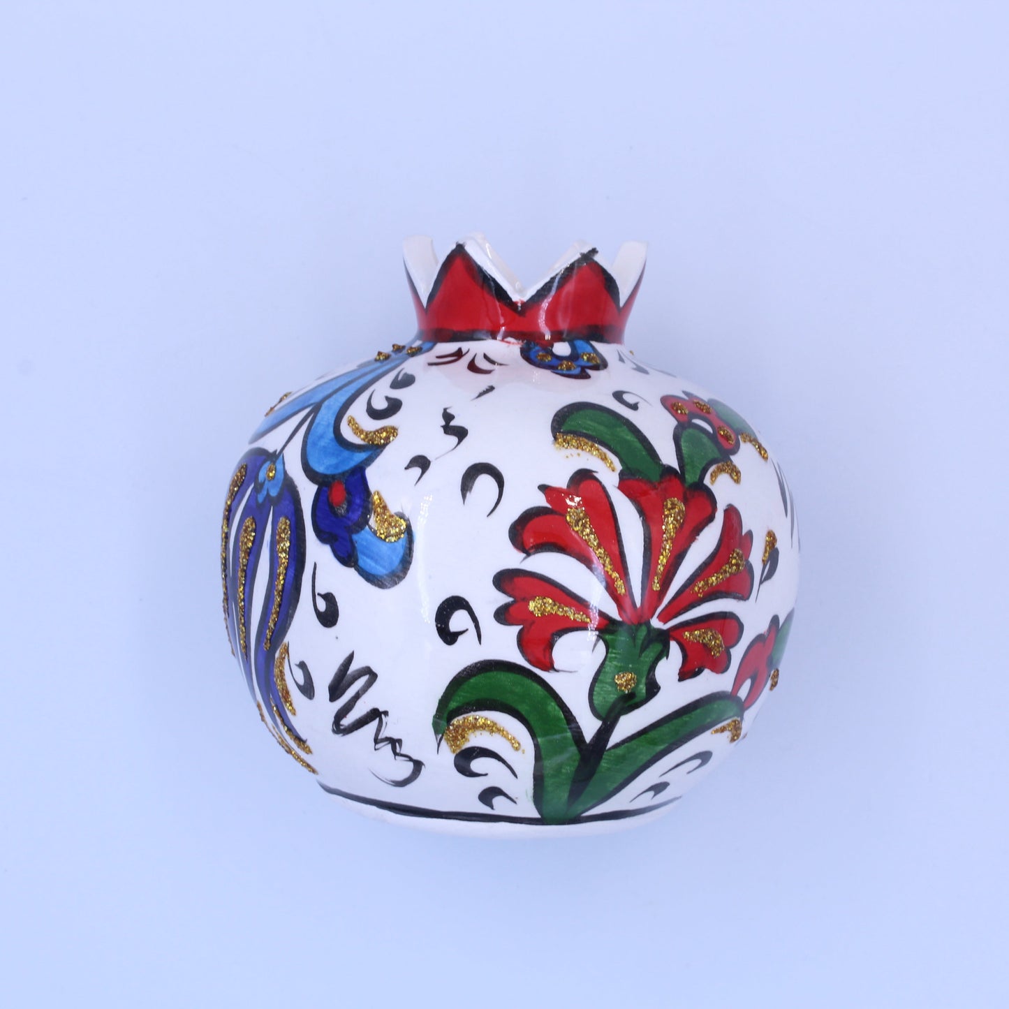 Decorative ceramic pomegranate with colorful floral patterns on a light blue background