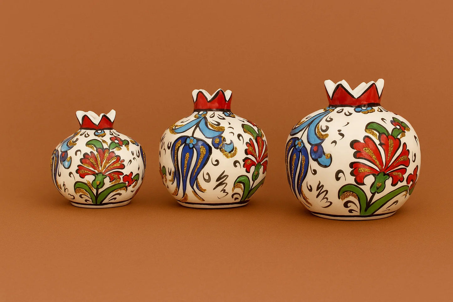 Three decorative ceramic pots with floral patterns on a brown background